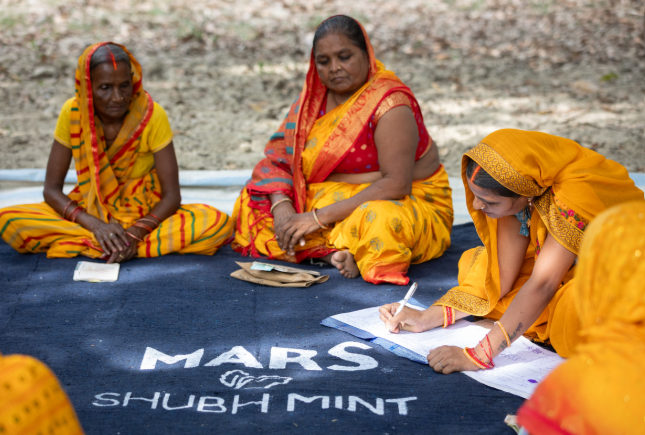 Women farmers in India sit together and take part in the Shubh Mint program.